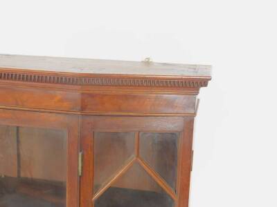 A George III mahogany hanging display cabinet, with dentil moulded cornice above a plain frieze, the slightly canted front, with lozenge astragal glazed single central door and fold opening conforming side panels, enclosing three shallow shelves, 97cm H, - 2