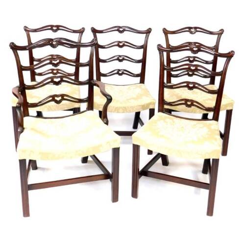 A set of five George III mahogany dining chairs in the Chippendale manner, including carver, having scroll terminal cresting rails, pierced and carved ladderbacks, moulded concave shoe piece, overstuffed concave seat, moulded and chamferred square foreleg