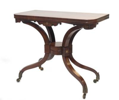 A fine Regency rosewood card table attributed to George Oakley, the baize lined, rounded rectangular fold over top, with satinwood crossbanding, scrolling frieze with brass inlay, on sabre supports joined by a central circular boss which performs a scisso