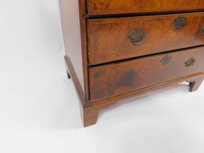 A George II walnut chest, of two short and three long graduated drawers, the top with figured quarter veneered central panel within herringbone banding, further banding to the drawers and with later brass handles having pierced back plates, on bracket fee - 4