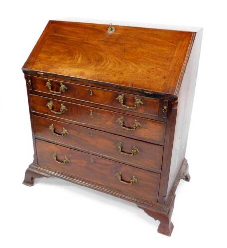 A George III North Country mahogany bureau, the fitted interior with stepped drawers, pigeon holes and a central cupboard, enclosed by a plain fall and having four graduated drawers below with cast brass rococo scroll handles, on ho-ho bird back plates, w