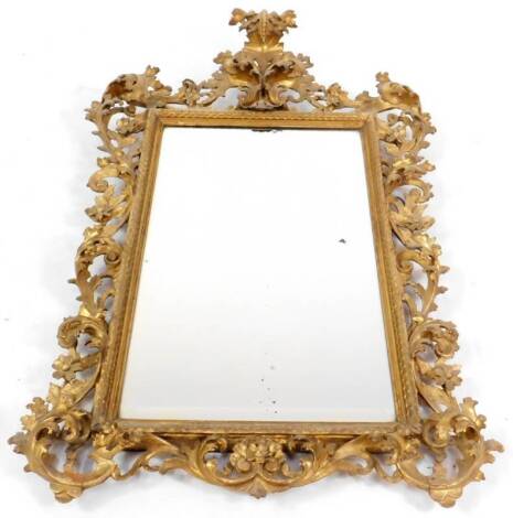 A large 19thC Florentine giltwood mirror, with a cascading foliate scroll crest and set with a bevelled rectangular plate within a scale pattern inner frame and further foliate scrolls and flower heads, 124cm H.