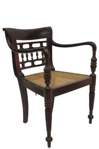 A 19thC Anglo-Indian colonial carver chair, with stylised pierced and galleried back, scroll arms with reeded supports cane seat, with squab and reeded forelegs, 82cm W.