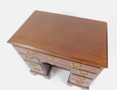 A George III mahogany dressing table, with moulded border and a brushing slide above a shallow single drawer and with six graduated small drawers flanking a recessed cupboard, with pierced brass handles, on shaped bracket feet, with handwritten note appli - 2