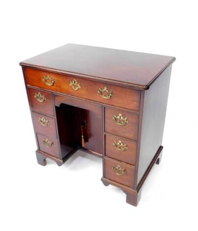 A George II mahogany kneehole desk or dressing table, with moulded and rounded rectangular top, oak lined frieze drawer over an apron drawer and cupboard beneath, flanked by three drawers each side on bracket feet, 75cm H, 77cm W, 48cm D.