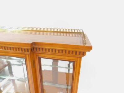 A late Victorian Sheraton revival satinwood and marquetry display cabinet, with a pierced brass gallery to the break front upper cabinet, with two glass shelves and enclosed by a single bevel glazed door, stepped table base with classical urn and scroll i - 2