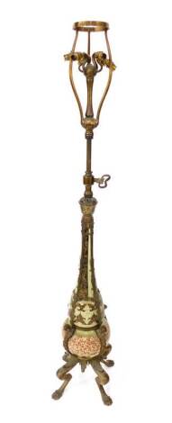 An unusual early 20thC electric brass standard lamp, with adjustable stem supporting a six branch cluster of bayonet fittings, and incorporating a decorative pottery body below of baluster form, with green and blue reserves and a band of fruiting foliage 