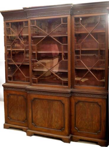 A 19thC mahogany breakfront cabinet bookcase in the Chippendale manner, with Greek key moulded cornice, blind fret frieze over three astragal glazed doors revealing adjustable shelves over a base with repeated frieze, and three moulded panel doors with fl