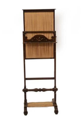An early Victorian rosewood screen, with pleated satin panel, on a rise and fall mechanism, single fret work shelf, over a ring turned double baluster stretcher joining the slab sides, moulded block base with applied roundel square feet, 90cm H minimum, 4
