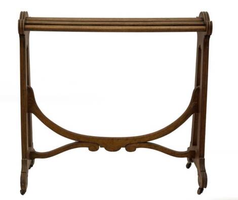 A Victorian walnut saddle stand, with slatted rail top, open slab sides, with reeded detail and scroll feet, on brass castors, and supported by a loop and scroll fluted stretcher, 90cm H, 92cm W, 47cm D.