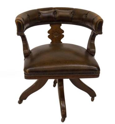 A Victorian walnut desk chair, with studded brown leather upholstery, roundel carved and fluted scroll supports, on swivel base with castors, 87cm W.