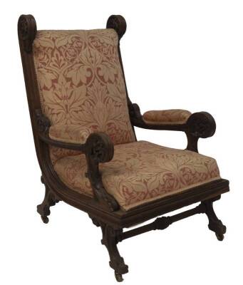 An early Victorian gothic revival oak library armchair in the manner of Augustus Welby Northmore Pugin, with William Morris style damask upholstery, stylised and carved supports, moulded base with carved and channelled legs with turned and carved stretche