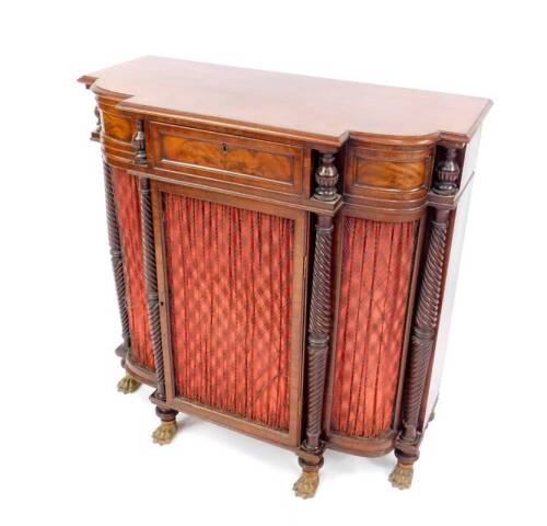 A Regency flame mahogany side cabinet in the manner of Gillows, the bowed breakfront fitted with a frieze drawer and central cupboard within tapered fluted columns and incorporating a single door with pleated curtain and wire lattice over, repeated to the