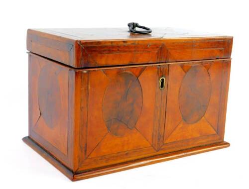 A George III cross banded mahogany rectangular tea caddy, decorated with quartered panels with central flame mahogany ovals, the hinged lid with brass ring handle, opening to reveal a twin compartment, raised on a plinth base, 13.5cm H, 21.5cm W, 13cm D.