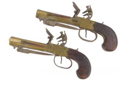 A pair of early 19thC brass blunderbuss flintlock pistols by George Wallis of Hull, with steel trigger guards and side mounted ramrods, walnut handles and sprung loaded bayonets to the underside, proof marks and numbered 1 and 2, 19cm (butt to muzzle). G