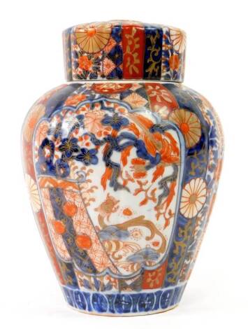 A late 19thC Imari vase and cover, of tapered and fluted design, painted with flowering shrubs and flower head designs, 23cm H.