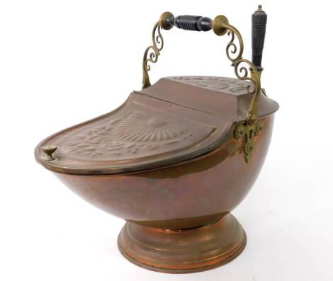 A Victorian copper coal box, with embossed hinged lid and top having foliate scroll and fluted decoration, and with brass handle over, and brass shovel, raised on a circular stepped foot.