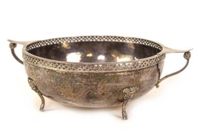 A George V silver two handled fruit bowl, with pierced border and hammered circular body raised upon four mask head and hoof feet, makers Albert Edward Jones, Birmingham 1926, 13oz, 19.5cm dia.