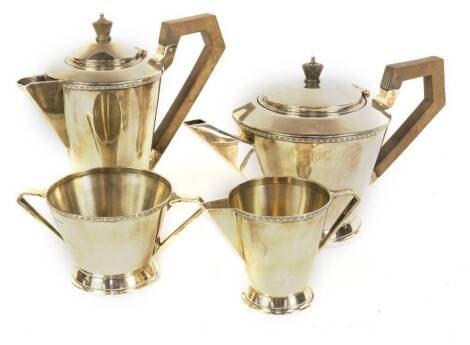 A late George V Art Deco silver four piece tea set, comprising teapot, hot water jug, milk jug and sugar basin, having tapered conical bodies with milled borders to the shoulders and rims, on spreading circular feet, Sheffield 1935, makers Cooper Bros & S