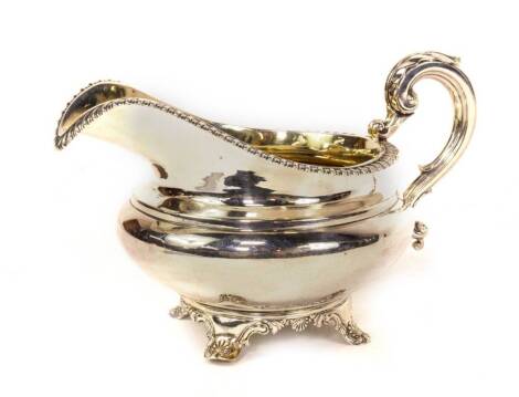 A William IV silver jug, of bellied circular design, with a gadrooned border and acanthus leaf capped scroll handle, raised upon four feet, with shell and scroll ornamentation, and with silver gilt interior, London 1832, makers possibly Charles Fox II, 7o