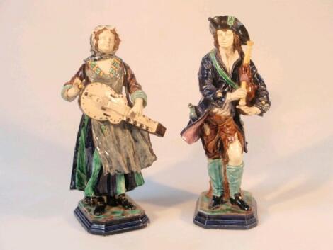 A pair of 19thC continental majolica musician figures on mottled stepped bases