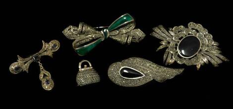 Five silver marcasite brooches, of varying design, comprising a handbag, a black agate floral spray, an amethyst Art Nouveau style bar brooch with drop, an Art Deco spray with black agate, and a bow brooch with green paste stone.