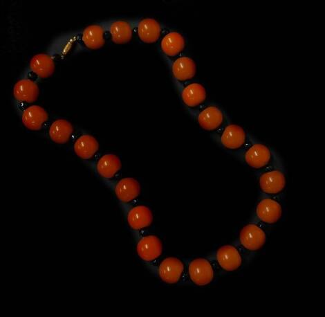 A butterscotch amber necklace, with spherical butterscotch amber beads each approx 2cm wide, with design of black etched beads between, on string strand, with screw in clasp, 72.4g all in.