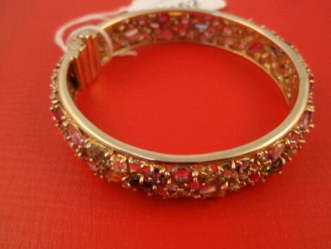 A heavy hinged bangle set overall with multi coloured gems