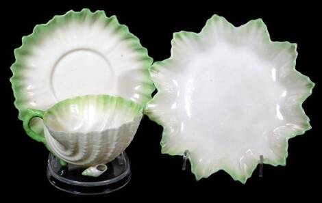 An early 20thC Belleek porcelain shell pattern trio, comprising of a cup, 12cm H, saucer and side plate, in green colours with black lighthouse, harp and dog mark beneath.