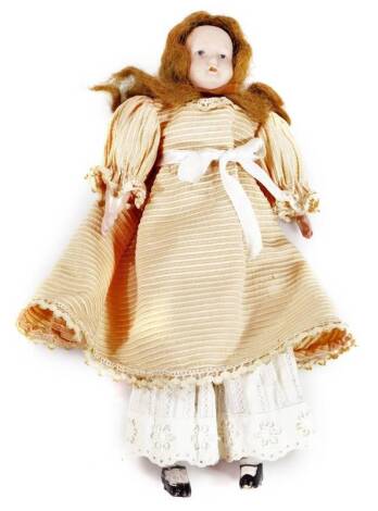 A late 19thC German bisque headed doll, with brown hair, fixed eyes and mouth, with articulated limbs, in period clothing, unmarked, 30cm H.