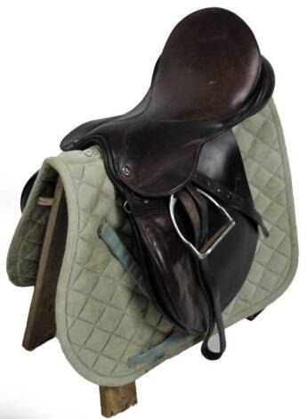 A leather horse saddle, with metal stirrups, 50cm W and a Cottage Craft saddling cloth, on stand.