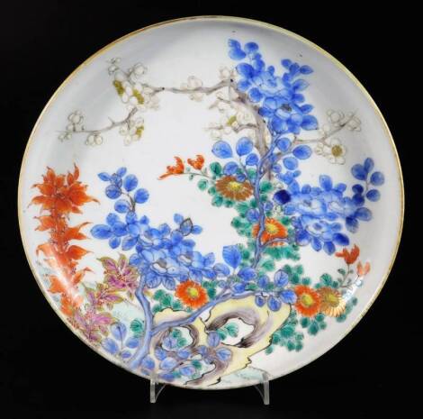 A 19thC Japanese porcelain dish, decorated with flowering trees and foliage, predominately in blue, green and orange, signed, 22.5cm Dia.