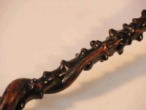 A rustic carved walking stick with serpentine shaft and handle carved in