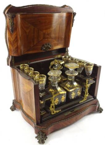 A 19thC French Kingwood and gilt metal liqueur set, the serpentine shaped box with a double hinged lid, enclosing three decanters and stoppers and various glasses, picked out in gilt, on scroll cast feet, incomplete, 34cm W.