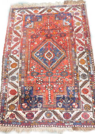 A Persian rug, with a central pole medallion, on a red ground with multiple borders, 166cm x 110cm.