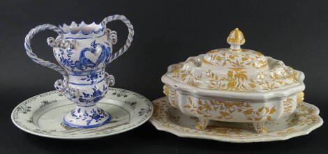 A Faience tureen, cover and stand, decorated with monkeys, birds, flowers etc., in beige, a Delft plate, painted with a galleon at sea and a Faience two handled cup. (3)