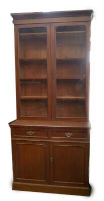 A late Victorian mahogany cabinet bookcase, with moulded cornice two glazed doors revealing adjustable shelves, over a two drawer and two door cabinet base with brass pierced backplate handles on plinth, 253cm H, 112cm W, 55cm D.