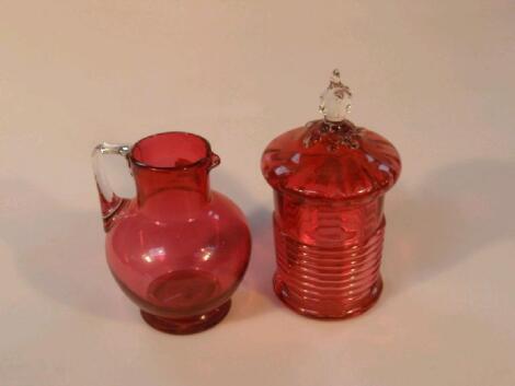 A cranberry glass circular jar and cover