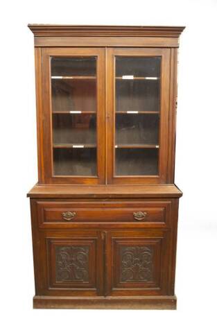 A late Victorian walnut cabinet secretaire bookcase, with moulded cornice, two moulded and glazed panelled doors, revealing adjustable shelves, over a fielded secretaire drawer with brass back plate loop handles and a fitted interior with pigeon holes and