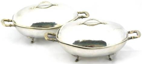 A pair of Danish hammered sterling oval entree dishes and covers in the manner of Georg Jensen, each with floral embossed handles, raised on four floral pattern feet, marked S.J. with Danish marks, white metal, 31cm W. (2)