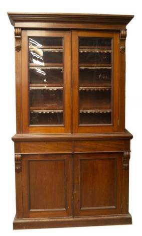 A late Victorian walnut cabinet bookcase, with moulded cornice and scroll supports enclosing two moulded and glazed doors, revealing leather fronted shelves with fleur-de-lys detail, over two freize drawers and two moulded panelled doors on plinth, 229cm 