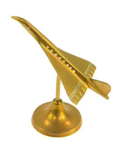 A brass desk stand modelled as Concorde, raised on a circular base, 16.5cm H.