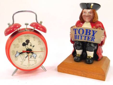 A seated Toby Bitter advertising figure, raised on a canted wooden base, 19cm H, together with a Disney Apollo Mickey Mouse alarm clock, red cased.