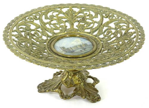 A Victorian gilt metal comport or tazza, with pierced decoration of scrolls, leaves etc., surrounding a central hand coloured print of The Houses of Parliament, on a circular column and pierced triform base, 20cm dia.