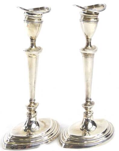 A pair of Edwardian silver navette shaped candlesticks, each with a separate sconce and a moulded base, loaded, Birmingham 1904, stamps for the Goldsmiths and silversmiths company, 20oz gross, 20cm H.