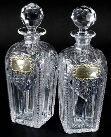 A pair of square section cut glass decanters and stoppers, each with a silver label for Gin and Whisky, 27cm H.