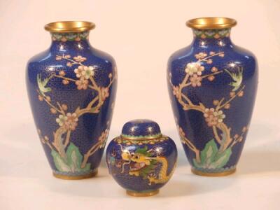 A pair of cloisonne vases with flowering branch and bird decoration on a blue ground