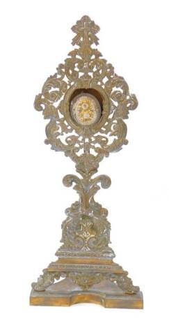 A Continental brass monstrance and reliquary, the monstrance of Baroque style with cast scrolling leaves, reserve coronet and monogram, raised on a shaped base, 41cm H, the oval reliquary, purporting to contain relics of St Thomas Episcop .. Cant, and Pop