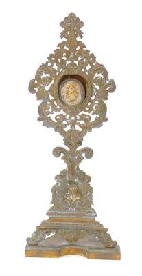 A Continental brass monstrance and reliquary, the monstrance of Baroque style with cast scrolling leaves, reserve coronet and monogram, raised on a shaped base, 41cm H, the oval reliquary, purporting to contain relics of St Thomas Episcop .. Cant, and Pop
