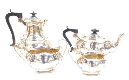 An Edward VII silver four piece tea set, of lobed and fluted form, raised on four bun feet, comprising teapot, cream jug, sugar bowl and covered hot water jug, maker Joseph Gloster Limited, Birmingham 1908, 48.77oz all in.